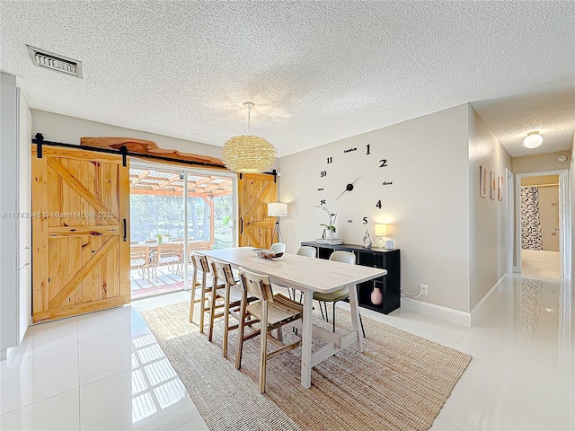 dining space featuring baseboards, a textured ceiling, light tile patterned flooring, a barn door, and visible vents