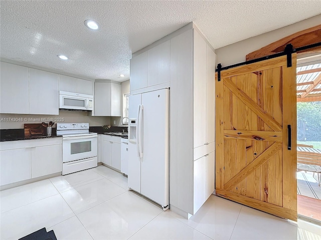 kitchen with recessed lighting, white appliances, a textured ceiling, dark countertops, and a barn door