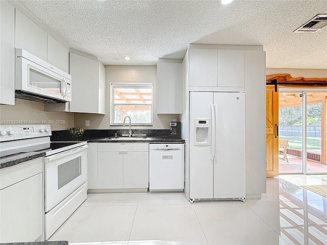 kitchen with plenty of natural light, white appliances, visible vents, and a sink