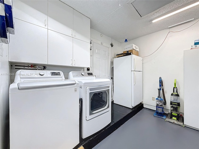 clothes washing area featuring separate washer and dryer, a textured ceiling, and cabinet space