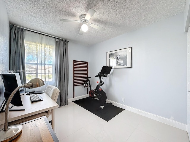 workout room featuring a textured ceiling, ceiling fan, baseboards, and tile patterned flooring