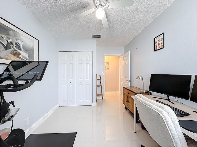 office space with visible vents, a ceiling fan, light tile patterned floors, and a textured ceiling