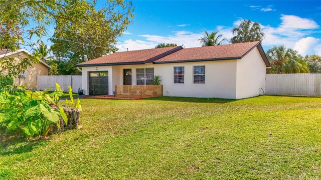 view of front of property with an attached garage, fence, a front lawn, and stucco siding