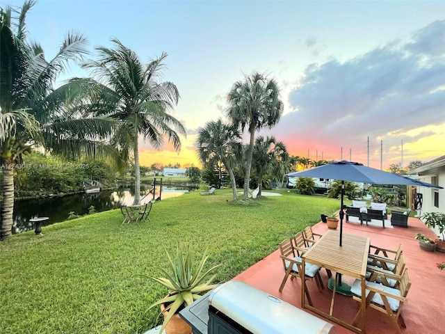 yard at dusk with an outdoor living space and a water view