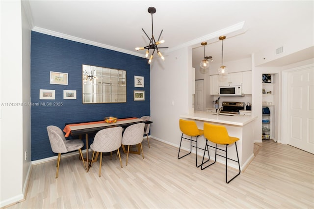 dining space with ornamental molding, a chandelier, and light wood-type flooring