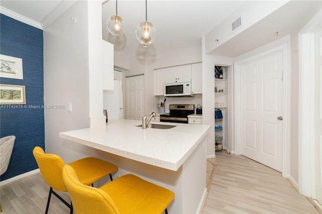 kitchen with a breakfast bar, sink, hanging light fixtures, electric range, and kitchen peninsula