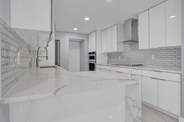 kitchen with white cabinets, sink, and wall chimney exhaust hood