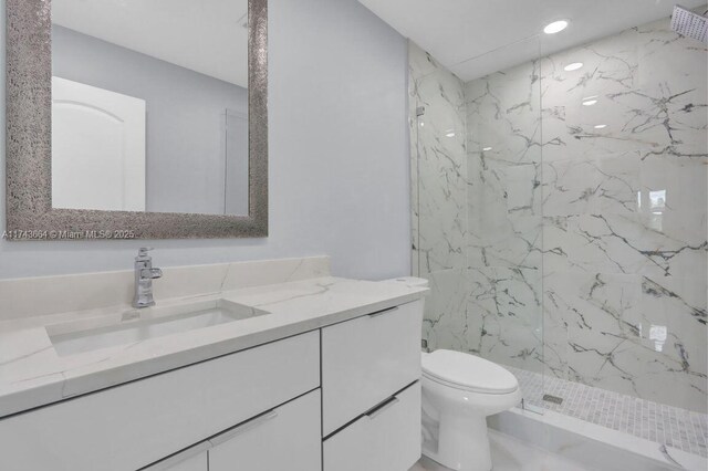 bathroom with vanity, toilet, and tiled shower