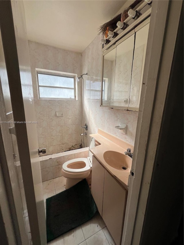 full bathroom featuring tile walls, tiled shower / bath combo, vanity, tile patterned floors, and toilet