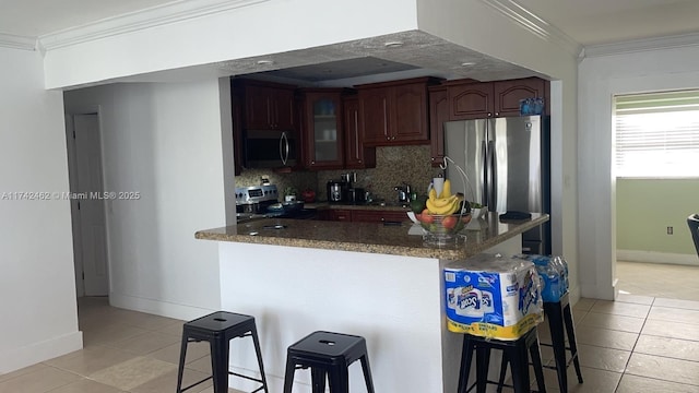 kitchen featuring a kitchen bar, crown molding, kitchen peninsula, stainless steel appliances, and backsplash