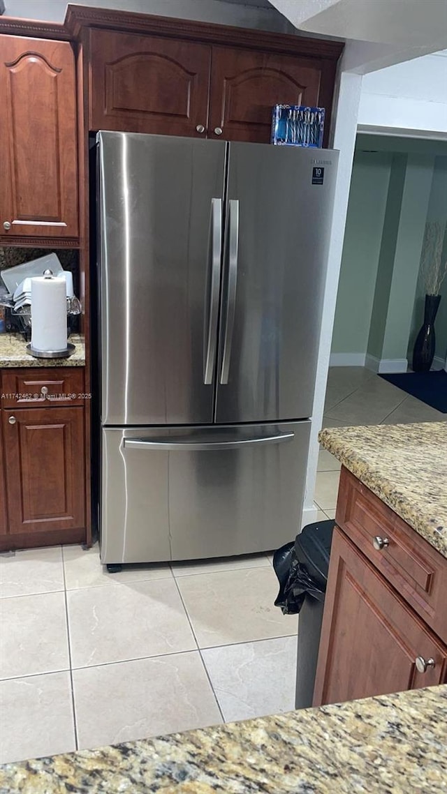 kitchen featuring light stone counters, light tile patterned floors, and stainless steel fridge