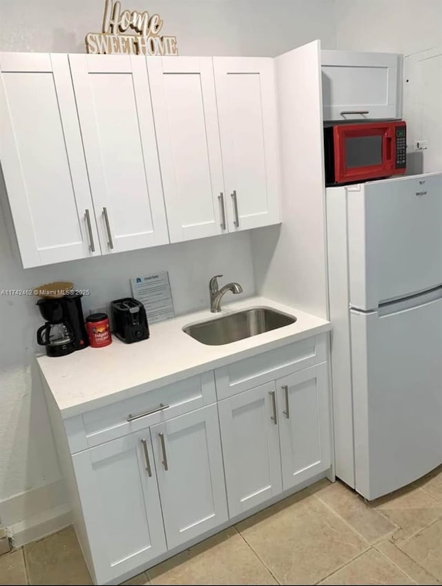 kitchen with white cabinetry, white fridge, and sink