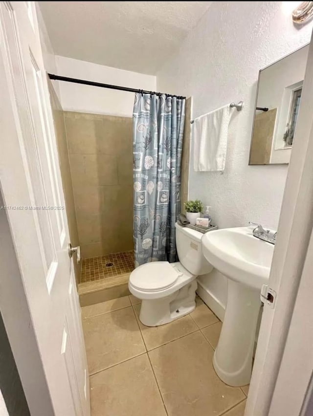 bathroom featuring walk in shower, tile patterned floors, and toilet