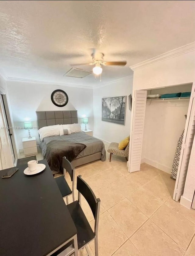 bedroom featuring a textured ceiling, light tile patterned floors, ornamental molding, a closet, and ceiling fan