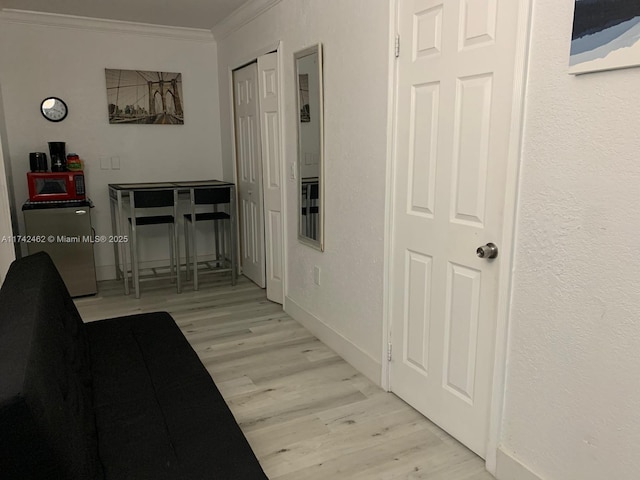 corridor with crown molding and light hardwood / wood-style floors