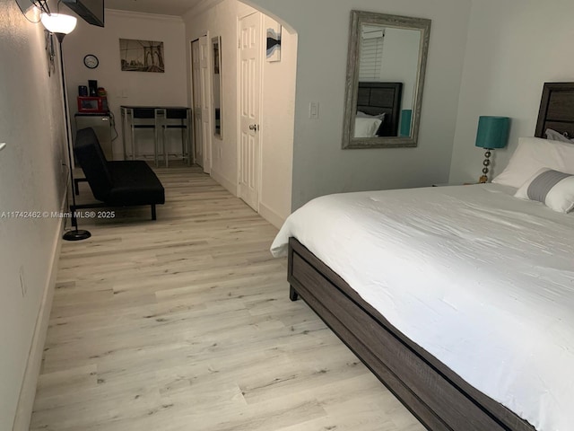 bedroom featuring ornamental molding and light hardwood / wood-style flooring