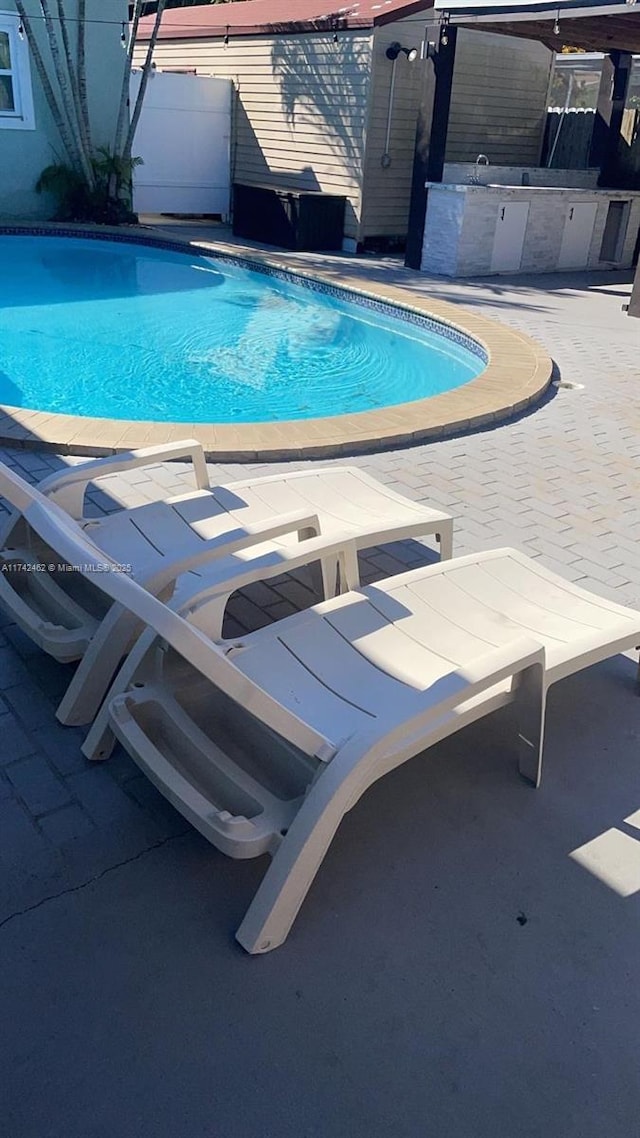 view of swimming pool with exterior bar, a patio, and exterior kitchen