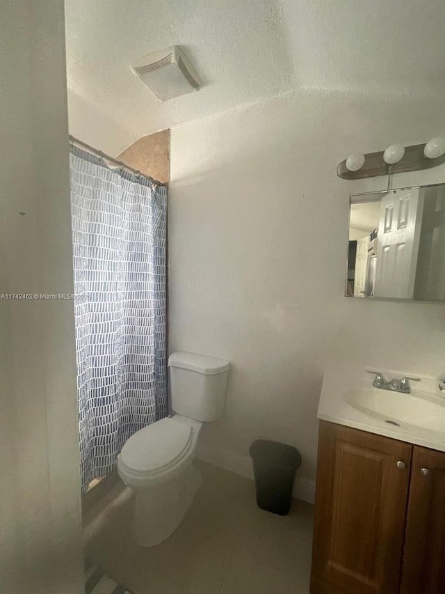 bathroom with vanity, tile patterned flooring, toilet, and walk in shower