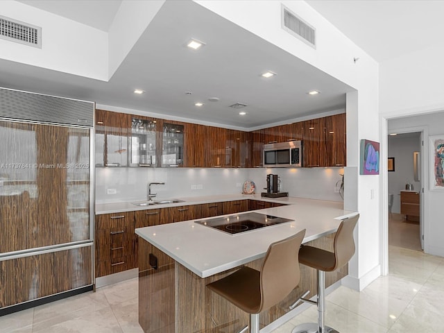 kitchen with visible vents, black electric cooktop, modern cabinets, a sink, and stainless steel microwave