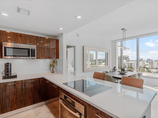 kitchen featuring modern cabinets, a peninsula, visible vents, light countertops, and stainless steel appliances