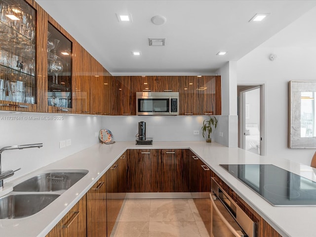 kitchen featuring light countertops, modern cabinets, a sink, and appliances with stainless steel finishes