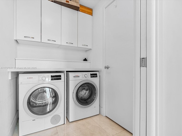 clothes washing area with light tile patterned floors, separate washer and dryer, and cabinet space