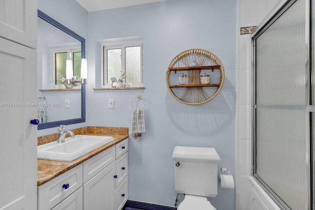 bathroom with toilet, enclosed tub / shower combo, and vanity