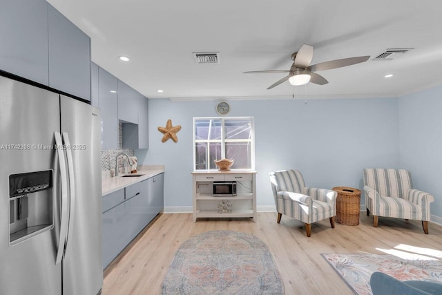 living area featuring a ceiling fan, visible vents, light wood-style flooring, and baseboards