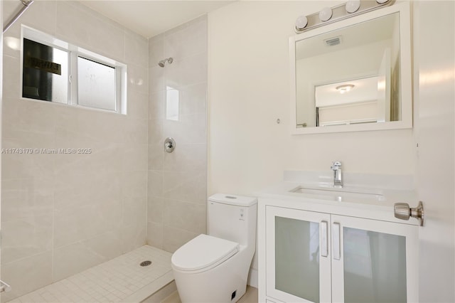 bathroom featuring vanity, a tile shower, and toilet