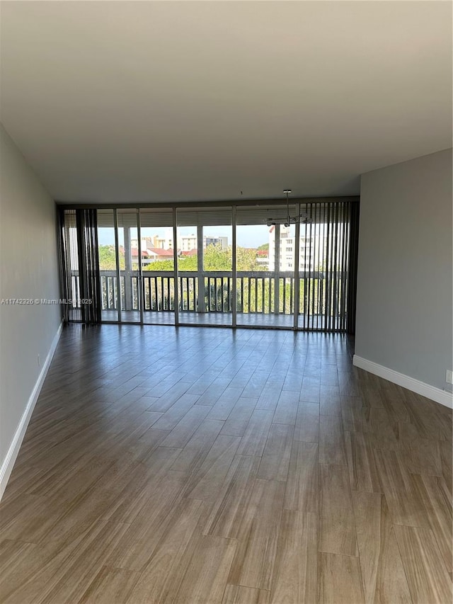 spare room featuring a wall of windows, a wealth of natural light, and baseboards