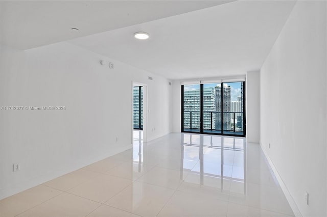 tiled empty room featuring a wall of windows