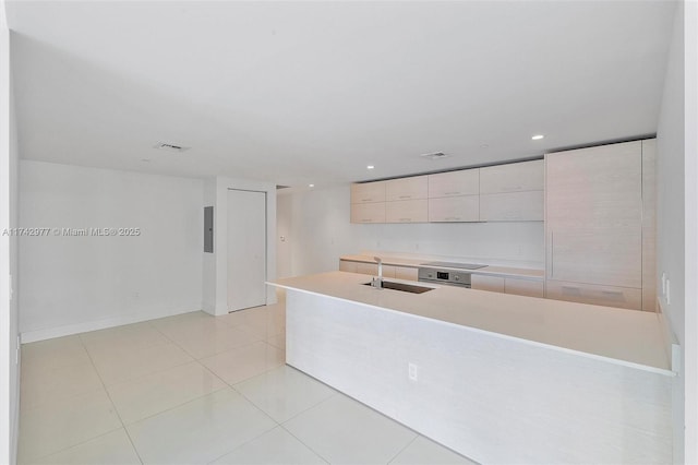 kitchen with light brown cabinetry, sink, light tile patterned floors, an island with sink, and black electric stovetop