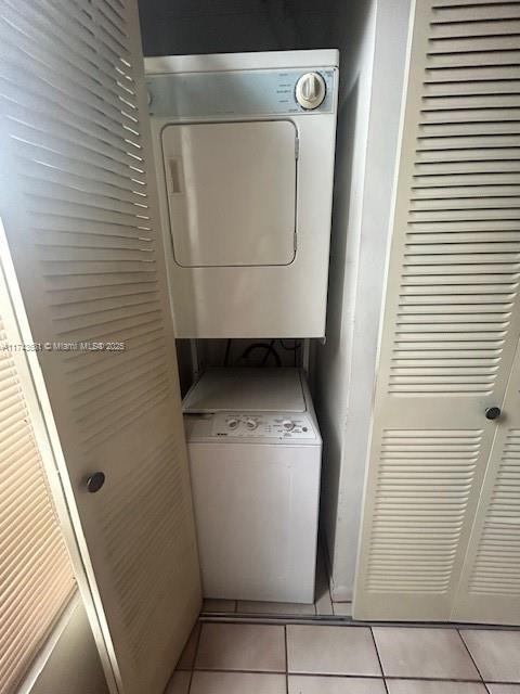 clothes washing area featuring stacked washer and clothes dryer and light tile patterned floors