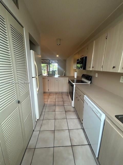 kitchen with light tile patterned floors, white appliances, and kitchen peninsula