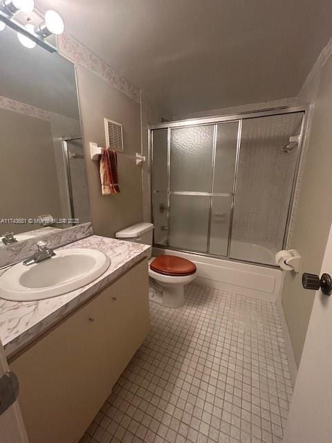 full bathroom with tile patterned flooring, vanity, combined bath / shower with glass door, and toilet