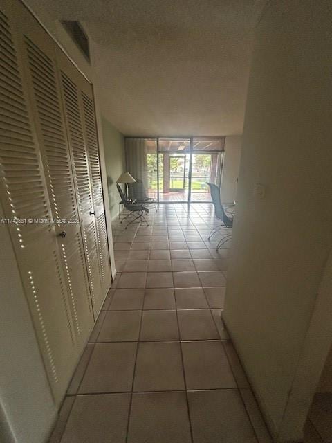 corridor with tile patterned flooring, expansive windows, and a textured ceiling