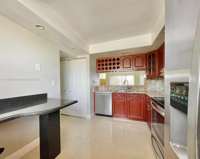 kitchen featuring appliances with stainless steel finishes, sink, light tile patterned floors, and decorative backsplash