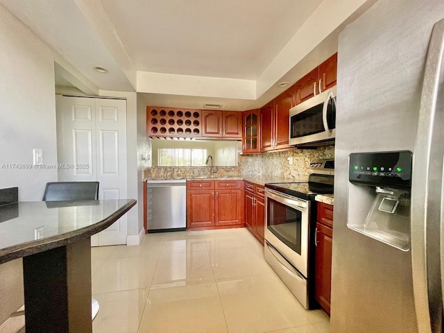 kitchen with light tile patterned flooring, a raised ceiling, sink, decorative backsplash, and stainless steel appliances