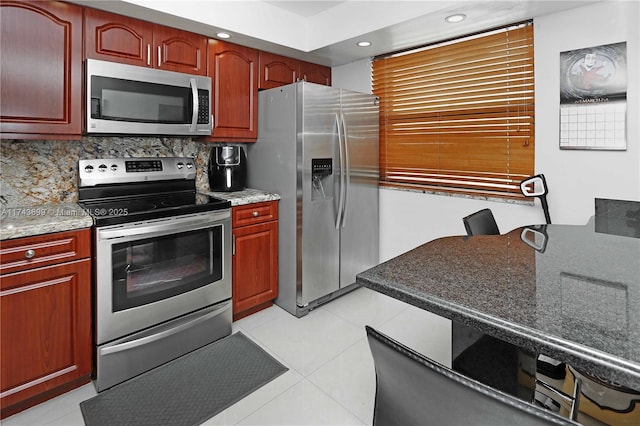 kitchen featuring tasteful backsplash, light tile patterned floors, stainless steel appliances, and stone counters