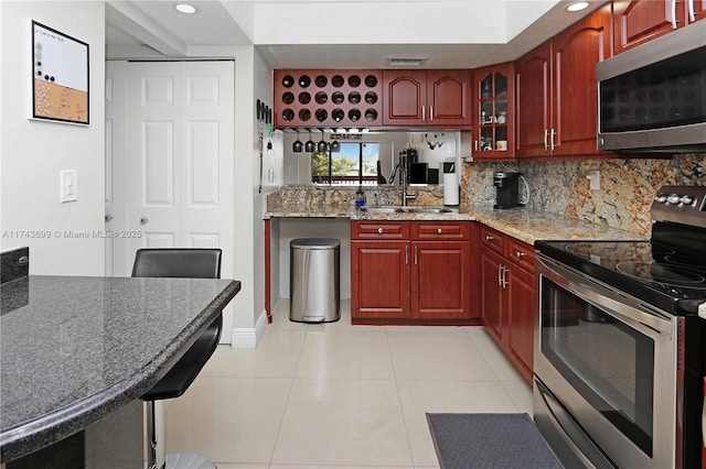 kitchen featuring sink, tasteful backsplash, light tile patterned floors, stainless steel appliances, and light stone countertops