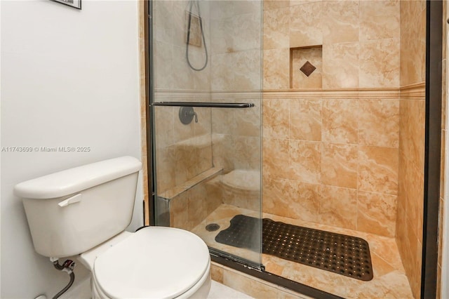 bathroom featuring a shower with door and toilet