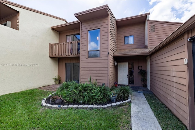 property entrance with a balcony and a lawn