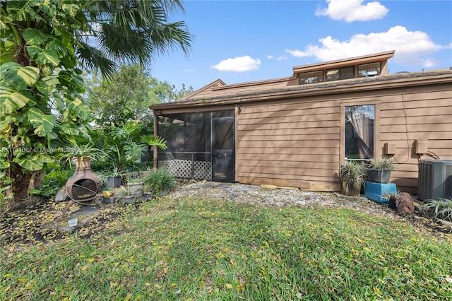 rear view of house featuring a sunroom, a lawn, and central air condition unit