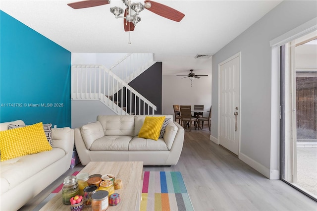 living room featuring ceiling fan, a textured ceiling, and light hardwood / wood-style floors