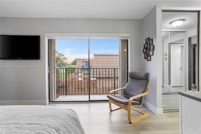 bedroom with light wood-type flooring, a textured ceiling, and access to outside