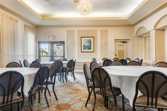 dining area with an inviting chandelier, a towering ceiling, and a raised ceiling