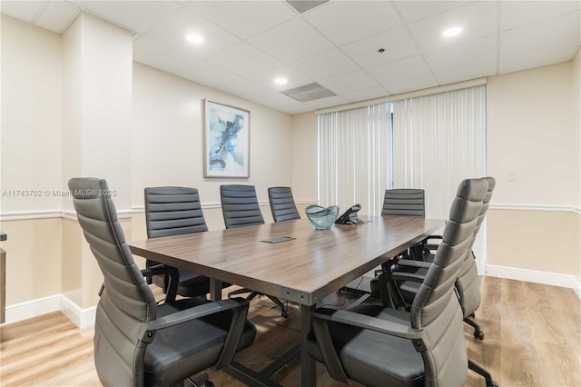 dining space featuring a drop ceiling and light hardwood / wood-style floors