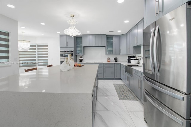 kitchen with stainless steel appliances, a kitchen island, hanging light fixtures, and sink