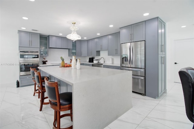 kitchen featuring sink, a breakfast bar area, appliances with stainless steel finishes, hanging light fixtures, and a kitchen island