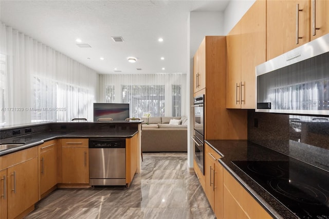 kitchen with stainless steel appliances, extractor fan, light brown cabinets, and dark stone countertops